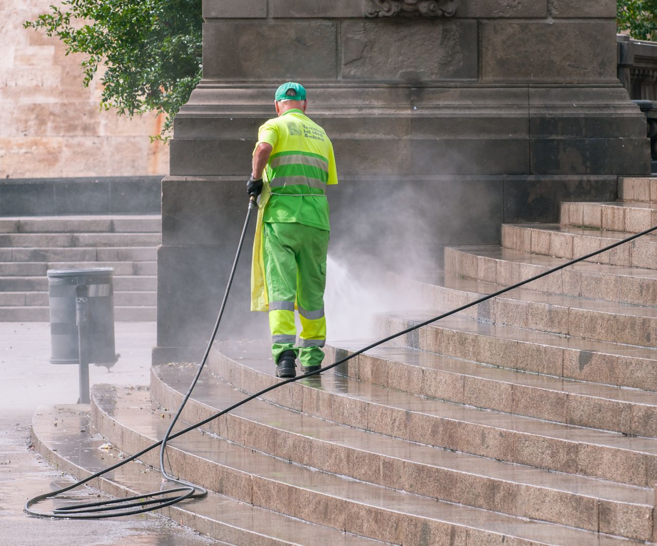 Portfolio A municipal worker power washing stone steps outdoors, ensuring cleanliness and maintenance.
